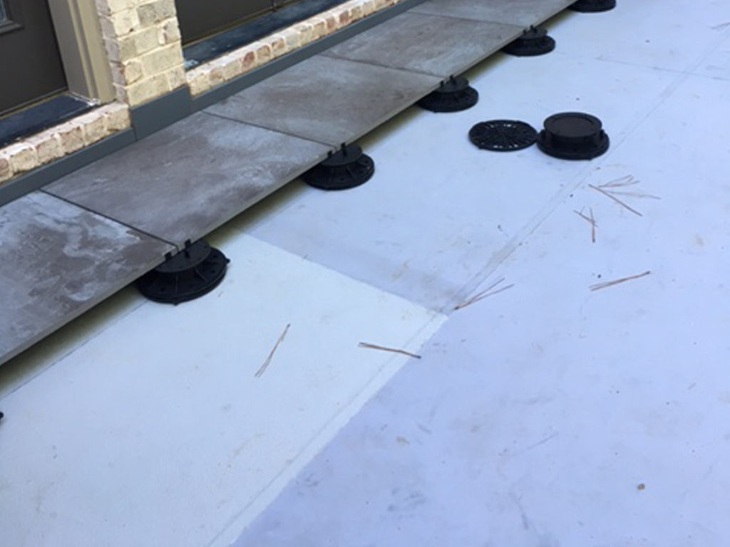 Floating deck system with concrete pavers on pedestals over the Duradek Plazadek waterproof membrane.